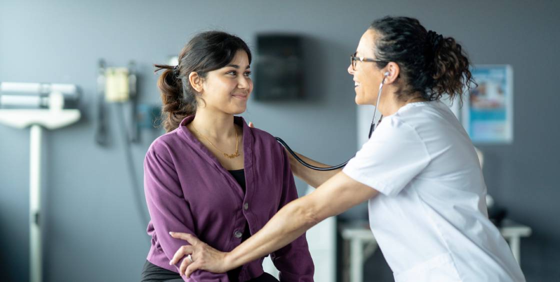Female doctor using stethoscope on patient